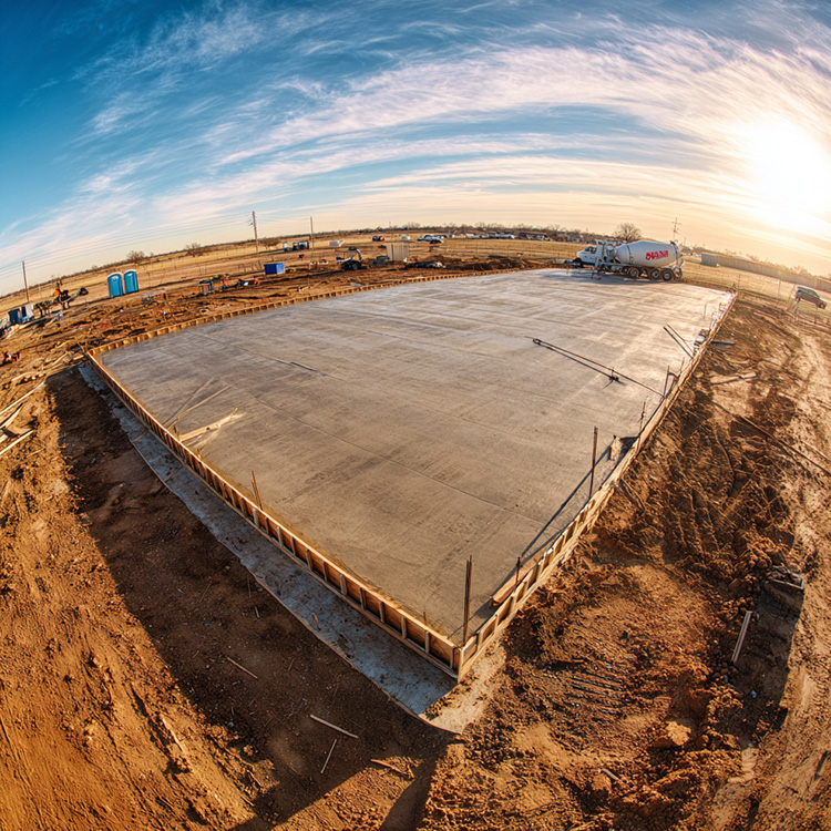 A newly poured concrete foundation slab at a commercial construction site in Abilene, Texas.